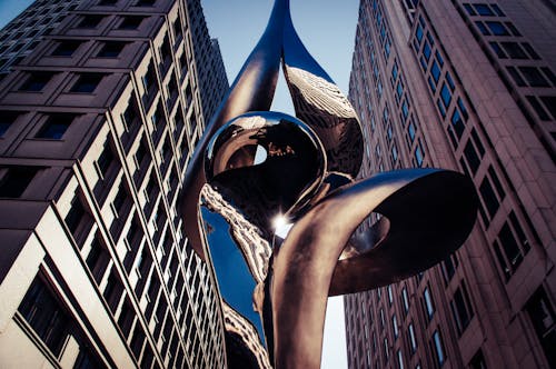 A sculpture of a spiral in front of tall buildings