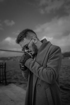 Fashionable man with sunglasses and coat on a cloudy day by the Bosphorus in Istanbul.