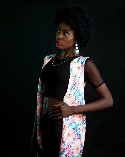 African woman in a colorful, stylish photoshoot on black background.