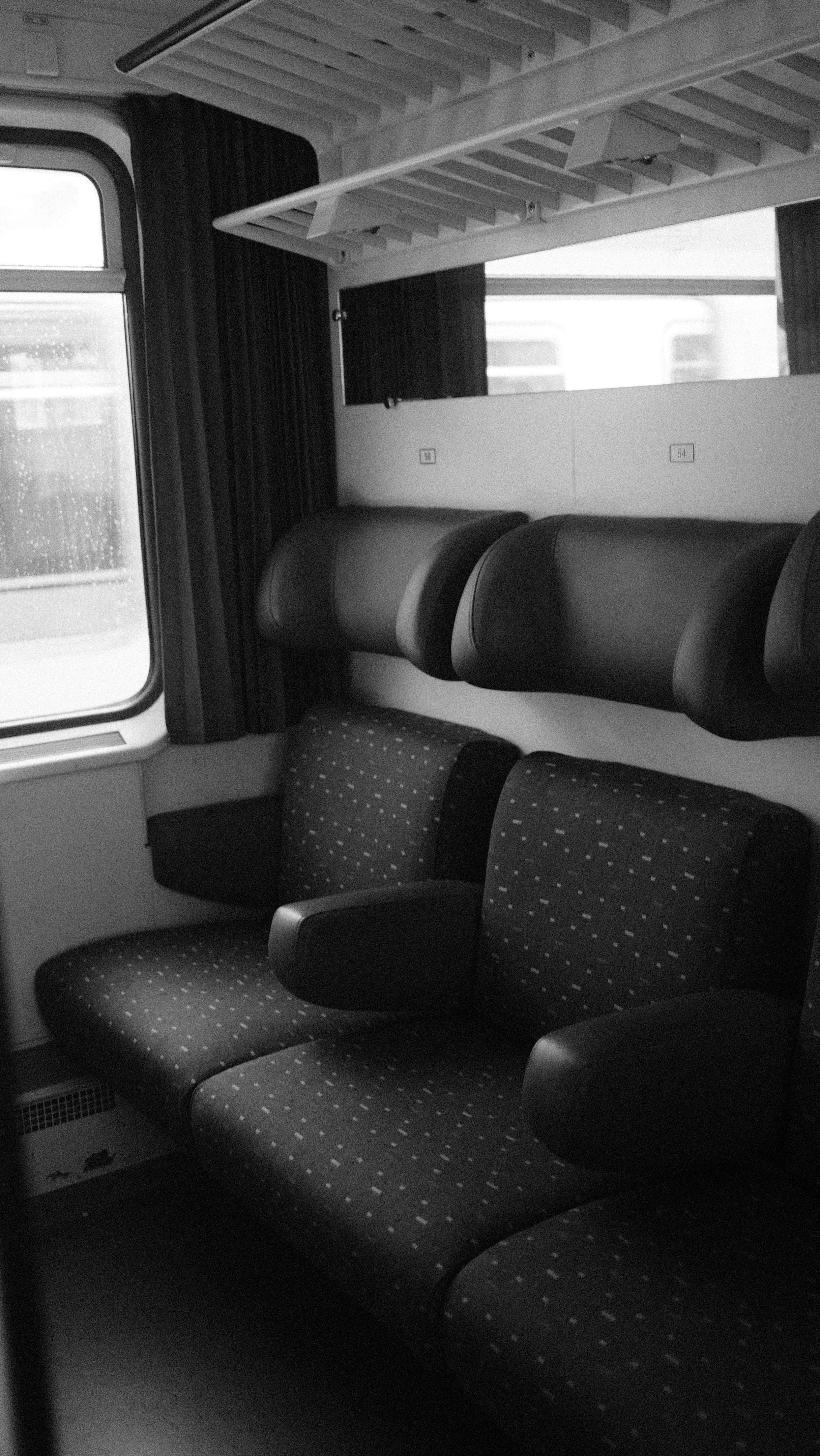 Black and white photo of an empty train compartment with plush seats in Brussels.