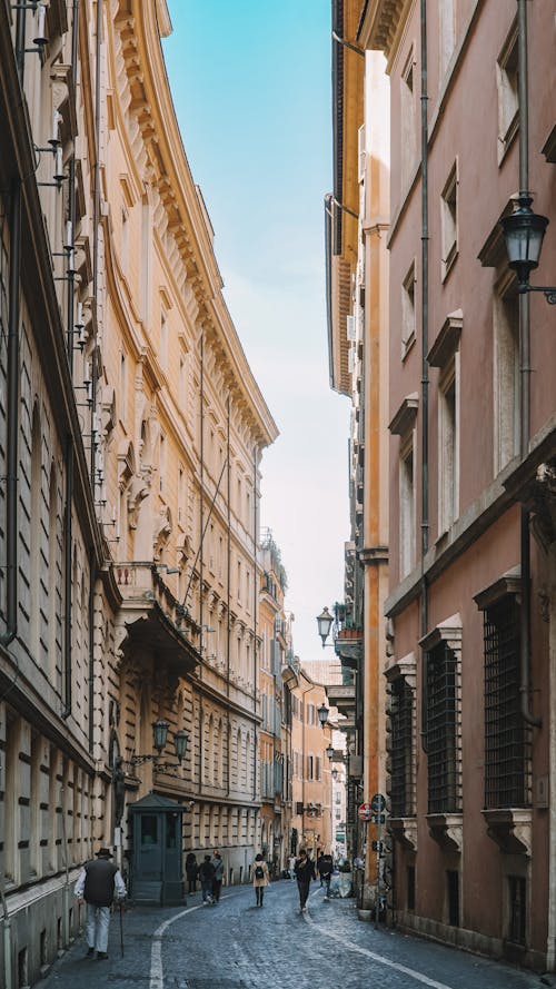 A narrow street with buildings and people walking