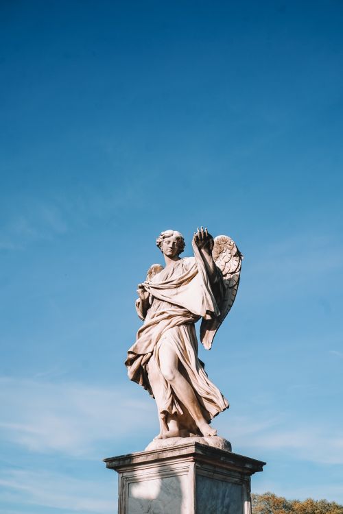 Free Magnificent angel sculpture on Ponte Sant'Angelo under a clear blue sky in Rome, Italy. Stock Photo