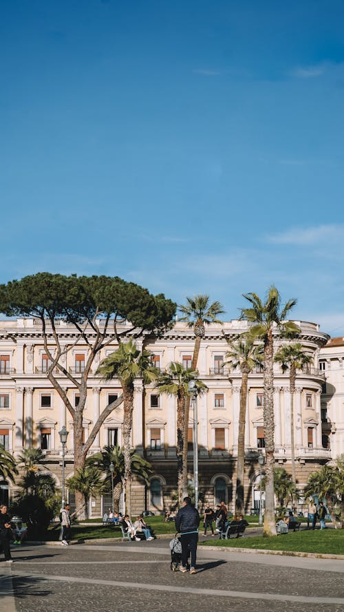 A person walking in front of a building with palm trees