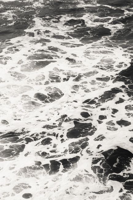 Dramatic ocean waves with splashing foam captured in black and white.
