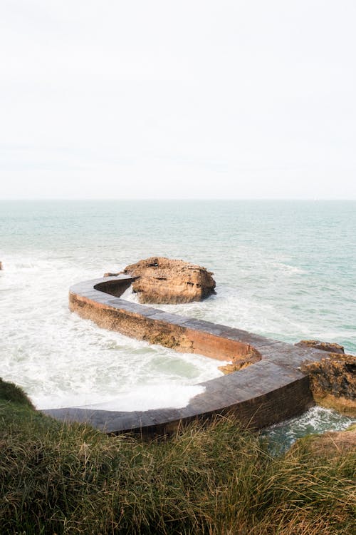 Free A man standing on a rock next to the ocean Stock Photo