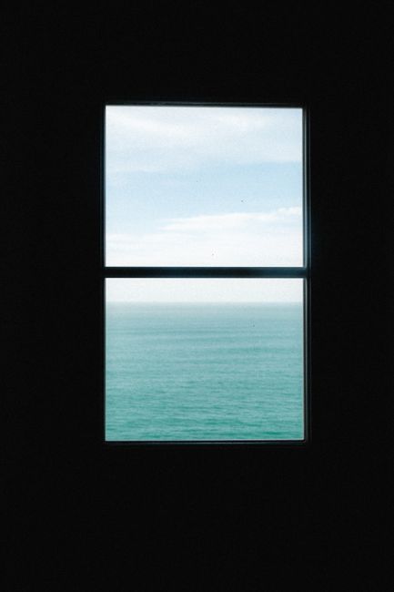 Calm ocean and sky view framed by a window, offering a peaceful seascape scene.