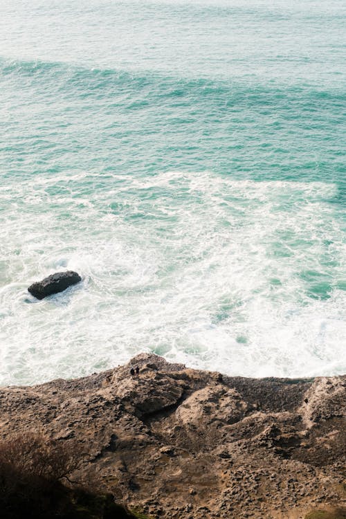 A person standing on a cliff overlooking the ocean