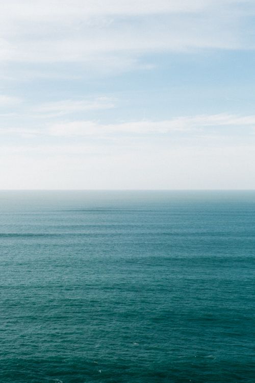 Free Tranquil seascape with soft clouds and endless ocean view, perfect for travel and relaxation themes. Stock Photo