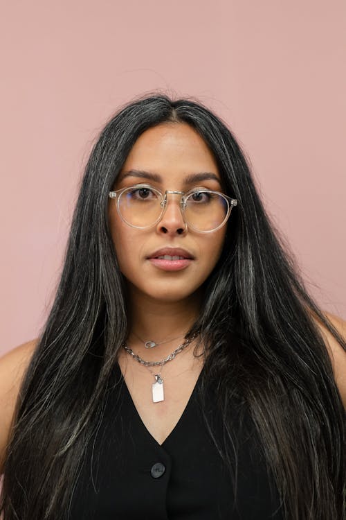 Free Portrait od a Pretty Brunette Young Woman in Glasses on a Pink Background Stock Photo