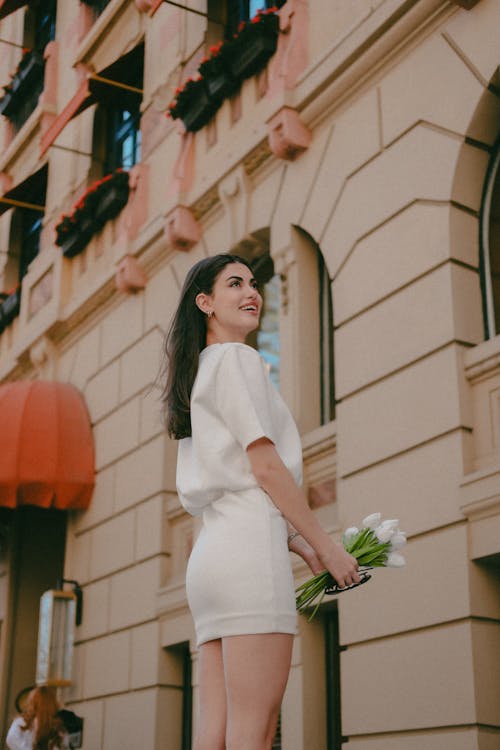 Free A woman in a white dress is standing on the street Stock Photo