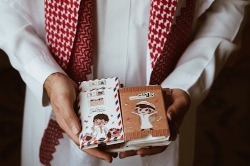 A man holding a book with a red and white scarf