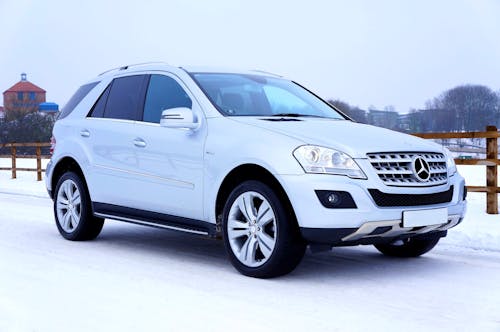 White Mercedes-benz Suv Parked Beside Brown Wooden Fence