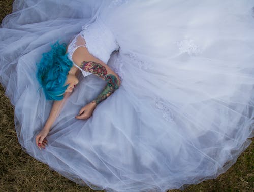 푸른 잔디에 누워 흰색 레이스 웨딩 드레스에 파란 머리 여자