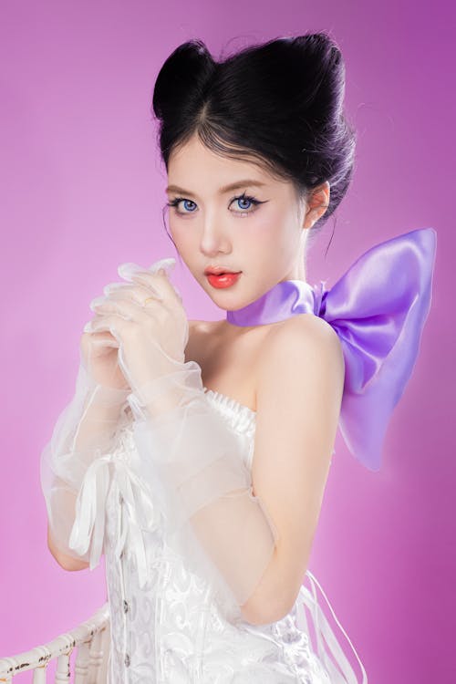 A beautiful young woman in a white dress and purple bow