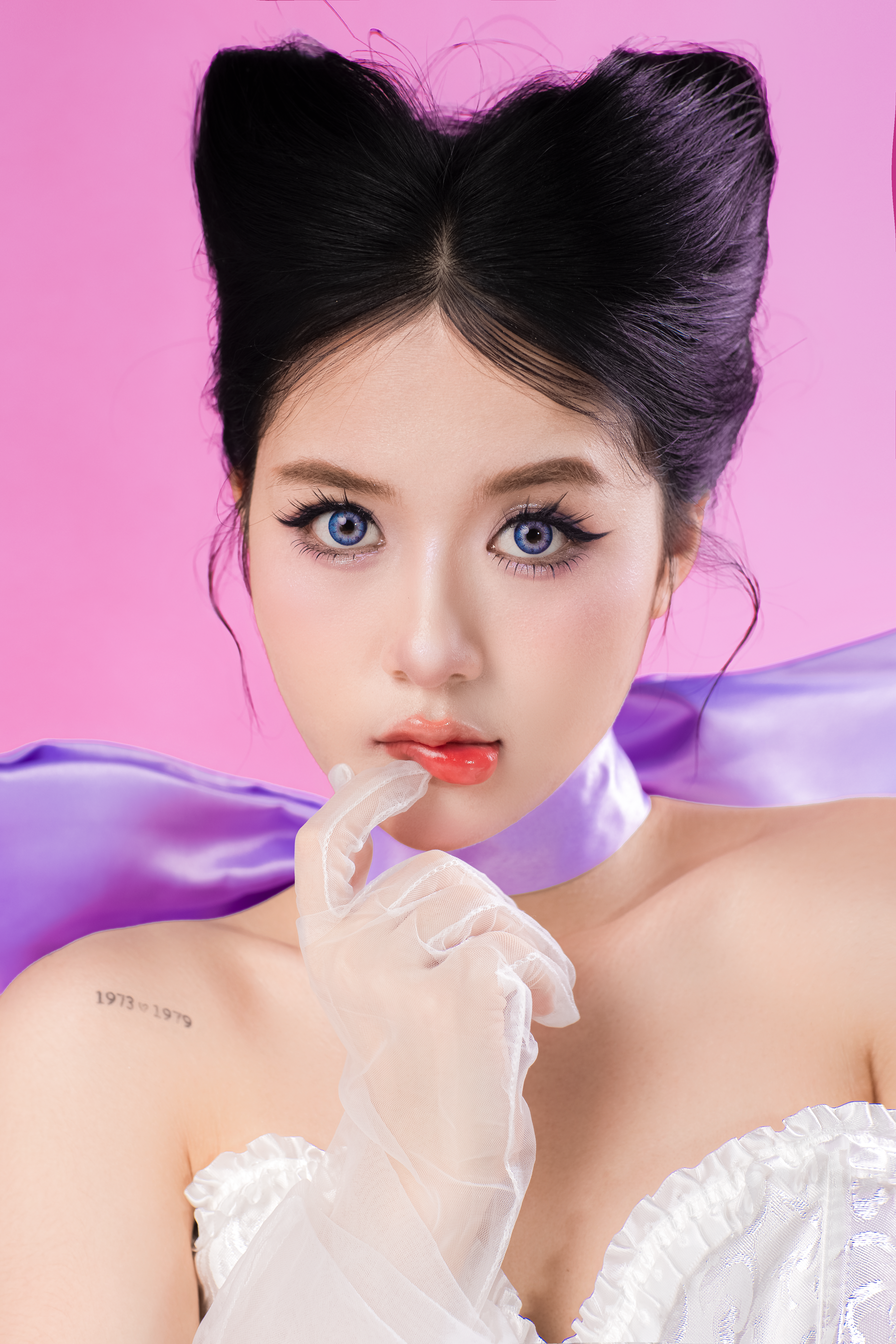 A captivating portrait of a young woman posing against a pink background in elegant fashion attire.