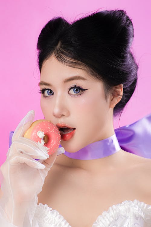 Young Asian Woman Posing with Donut on Pink Background