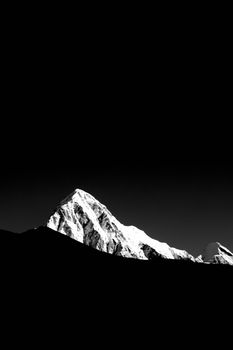 A striking black and white image of a snow-covered mountain peak under a clear sky.