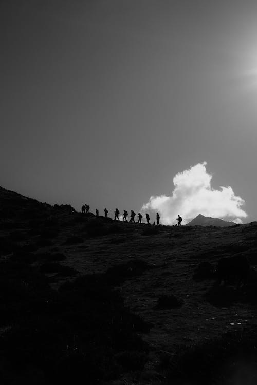 A black and white photo of people walking on a hill