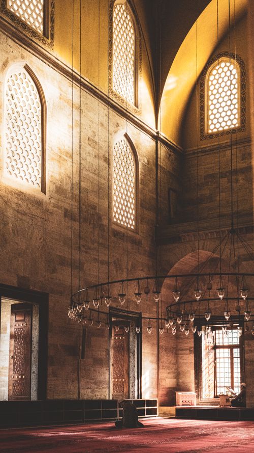 Free Warm sunlight illuminates the grand interior of Süleymaniye Mosque, showcasing its architectural beauty and religious ambiance. Stock Photo