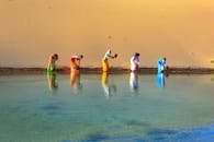 一群妇女穿着彩色服装，在晴朗的天空下从沙漠绿洲中取水