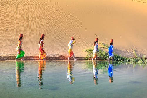 頭に鍋を持って水の近くを歩く5人の女性