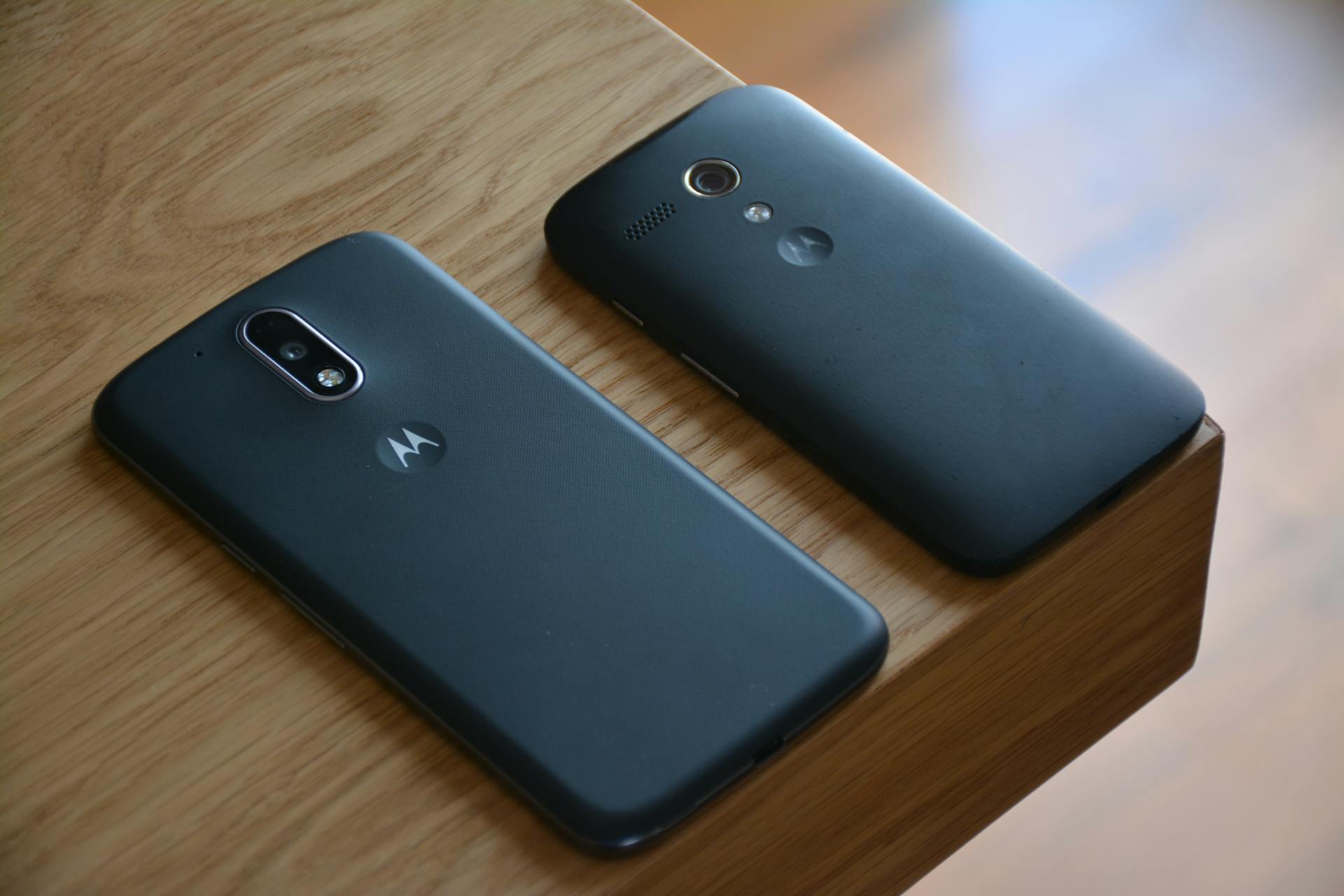 Two Motorola smartphones placed on a wooden table with natural lighting.