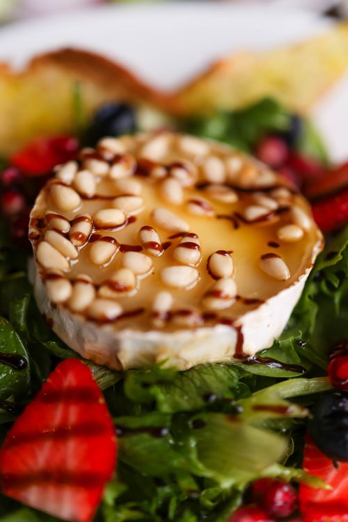 Free Delicious salad with goat cheese, pine nuts, and fresh fruits, topped with balsamic glaze. Stock Photo