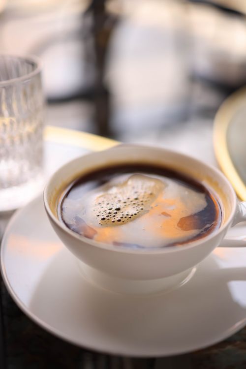 Free A steaming cup of coffee with swirls of cream, beautifully captured with a soft focus and warm lighting. Stock Photo