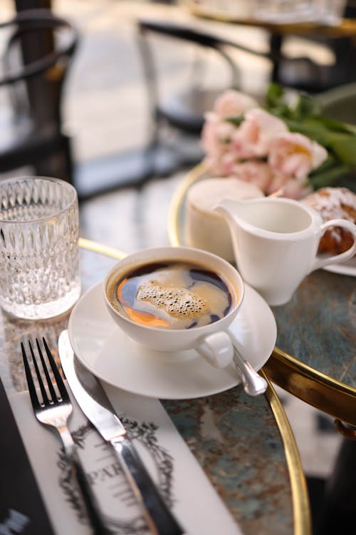 Free A coffee cup and saucer on a table with a fork and knife Stock Photo