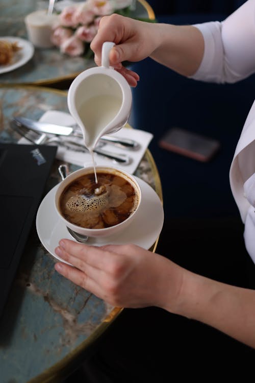 A woman pouring milk into a cup of coffee