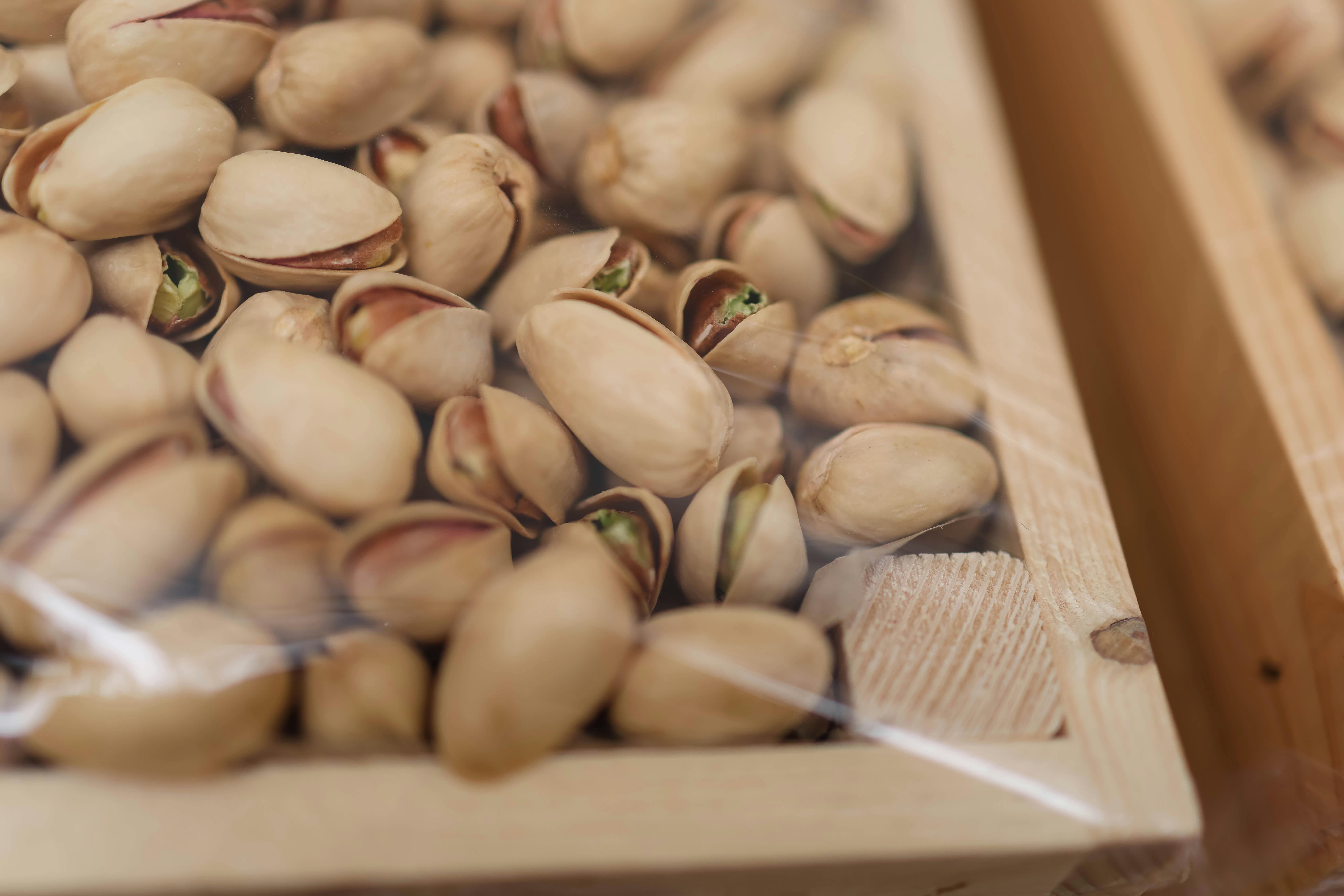 A detailed close-up shot of unshelled pistachios in a wooden box, perfect for food photography.