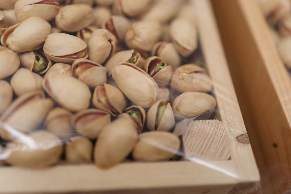 A detailed close-up shot of unshelled pistachios in a wooden box, perfect for food photography. - Where to Buy Quality Dry Fruits in Pakistan