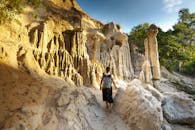 一位孤独的旅行者在明亮的天空下航行，眼前是令人惊叹的地质构造