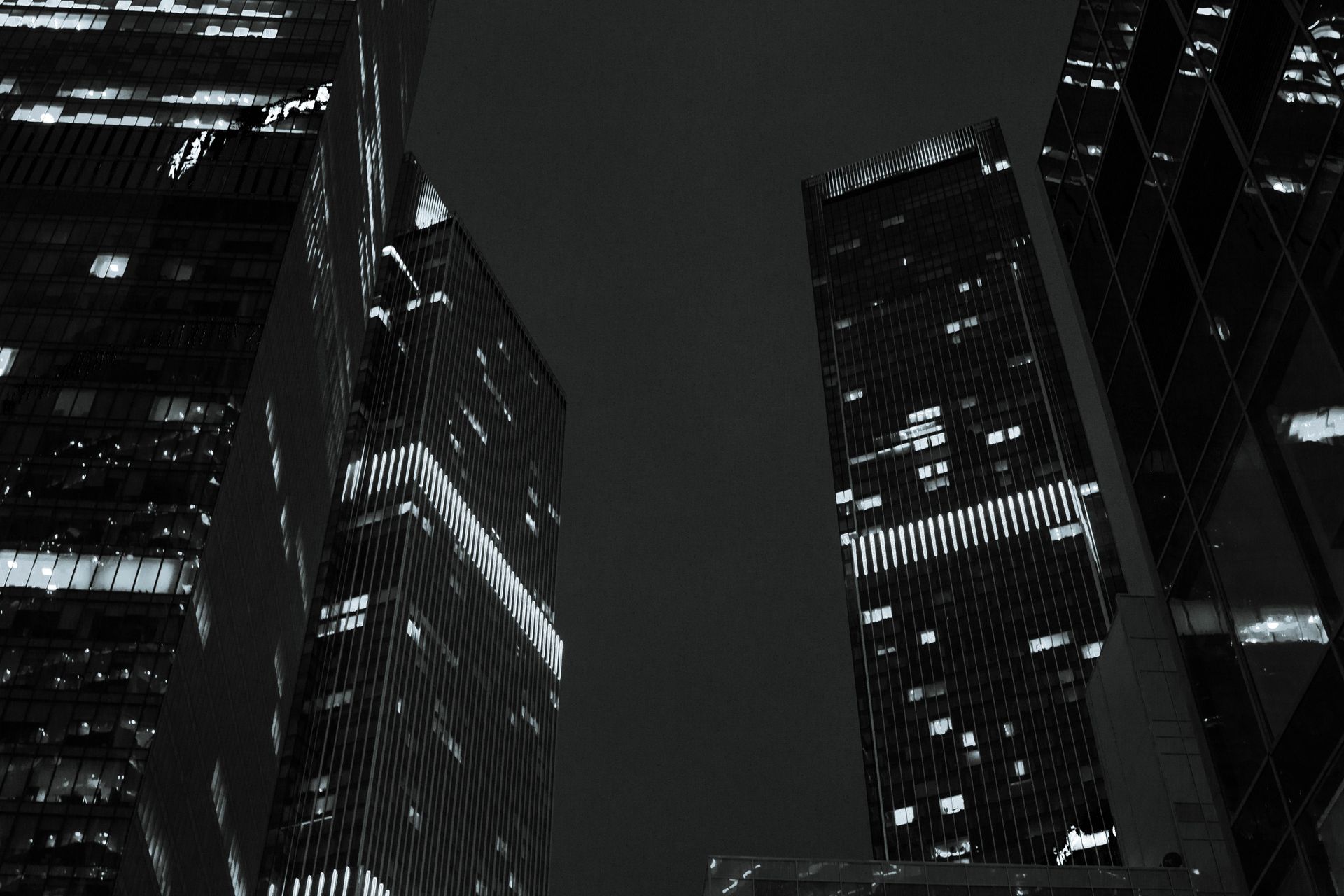 Looking up between illuminated glass towers at night