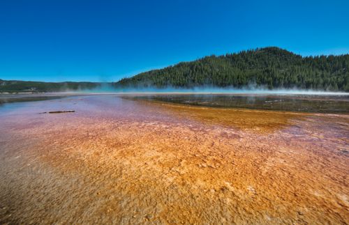 Free Vibrant geothermal pool landscape in Yellowstone National Park with steam rising. Stock Photo