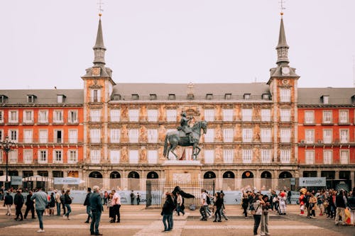 People are walking around a plaza with a statue in the middle