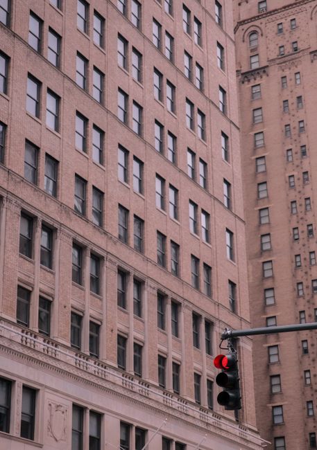 Angled view of a historic building facade with red traffic light in an urban setting.