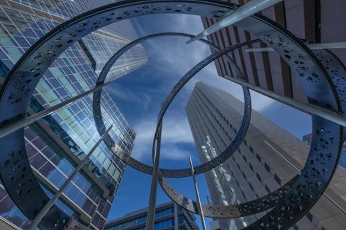 Free A circular metal sculpture in front of tall buildings Stock Photo