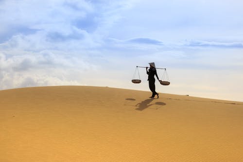 Woman Holding Yoke While Carrying Yoke on Desert