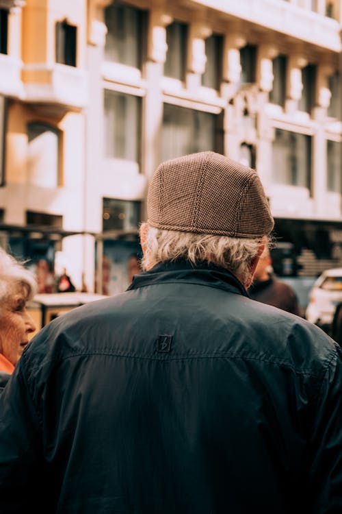 A man wearing a hat walking down a street