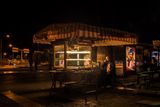 Lit food kiosk on a quiet street at night — photo by Ugur Cetin on Pexels