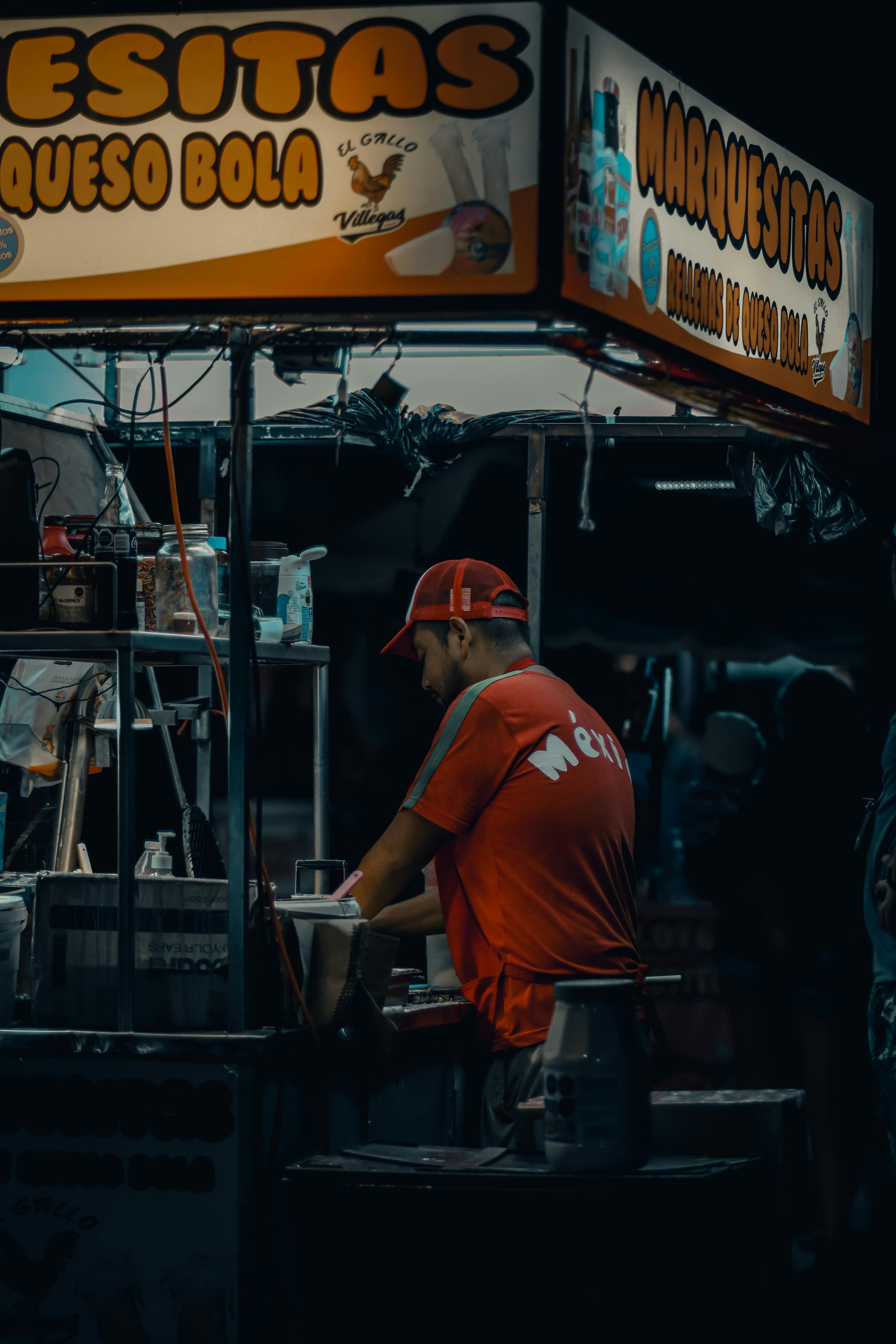 Candid shot of a street food vendor preparing snacks at a bustling urban market at night.