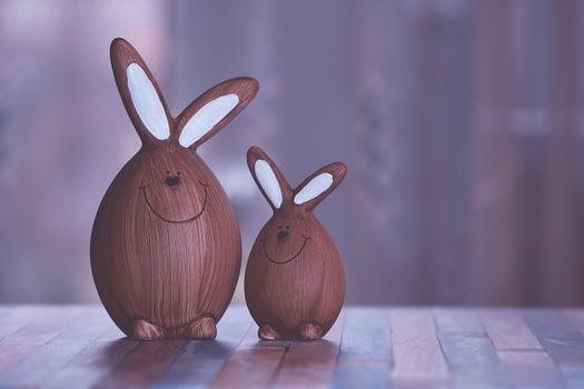 Two wooden Easter bunny figurines standing on a table with a soft focus background.