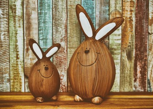 Charming wooden bunny figures with a colorful rustic wooden backdrop.