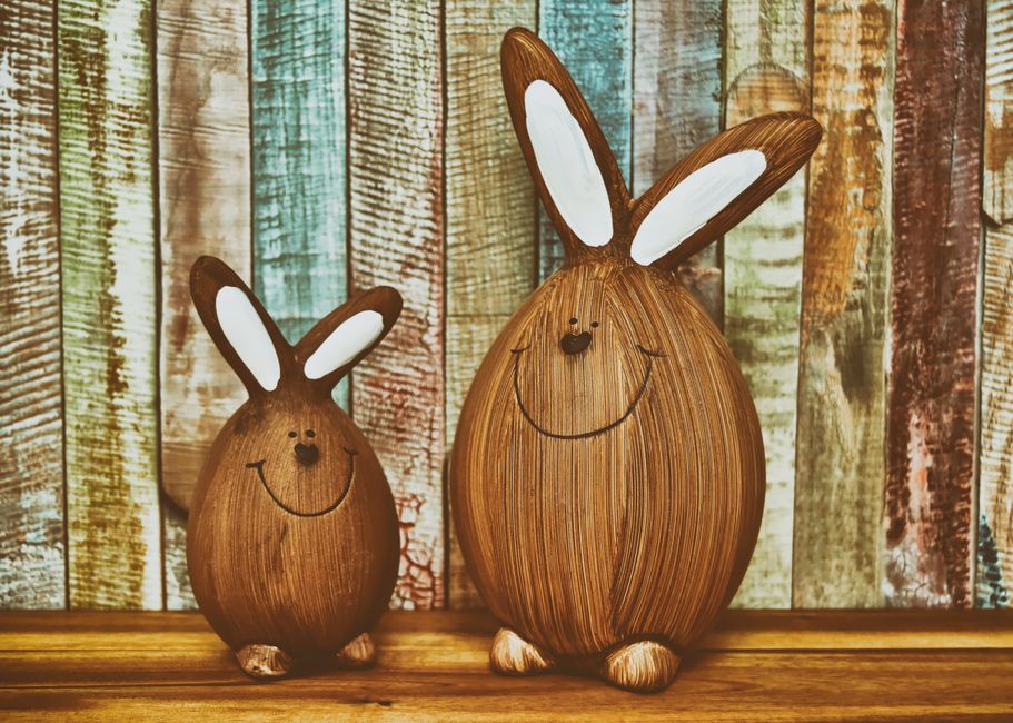 Charming wooden bunny figures with a colorful rustic wooden backdrop.