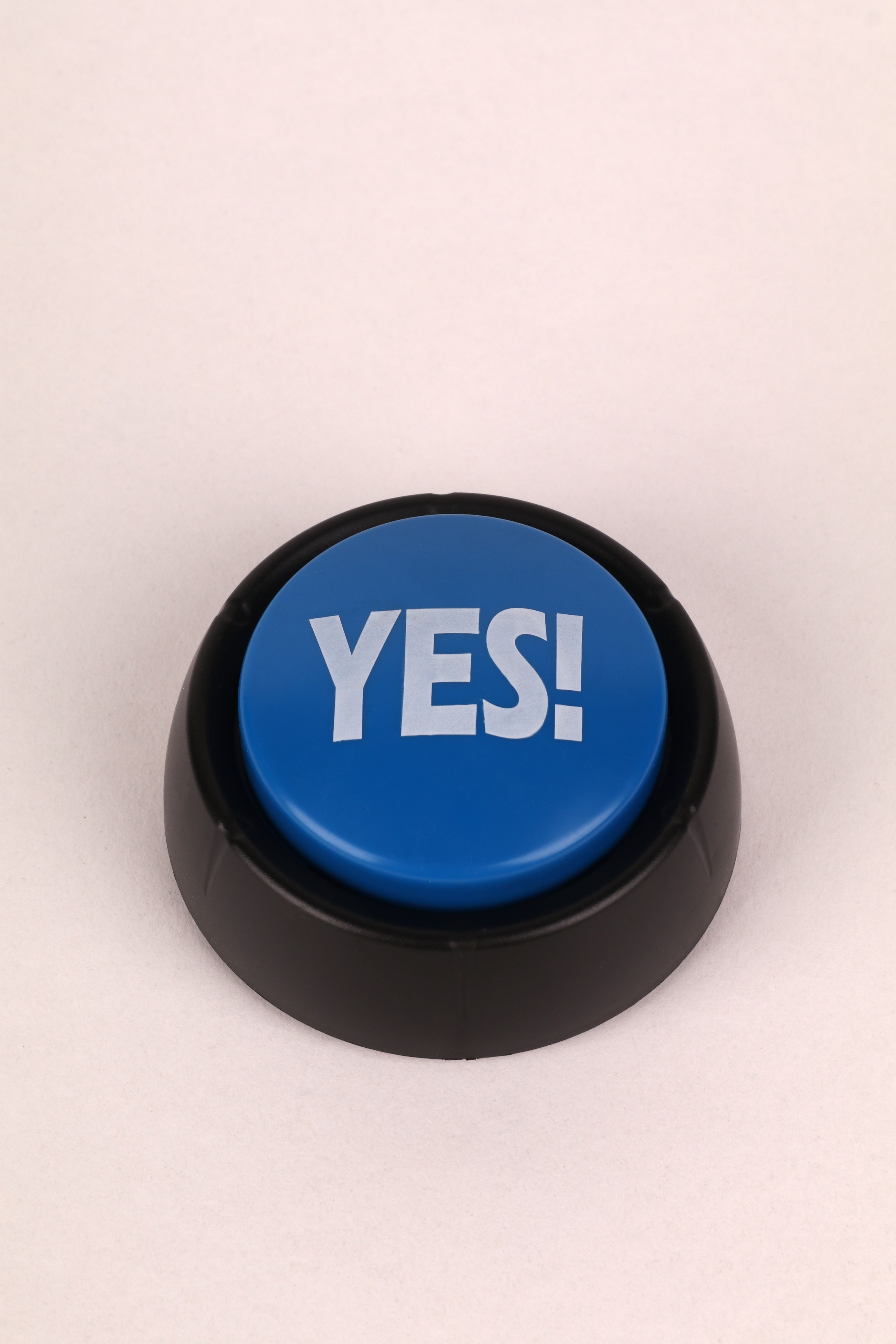 Close-up of a blue button with 'Yes!' text on a beige background, perfect for communication themes.