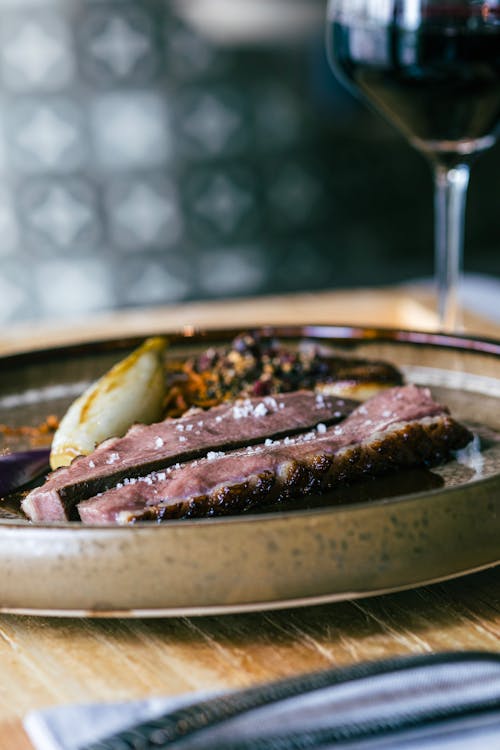 Free A plate with meat and vegetables on it next to a glass of wine Stock Photo