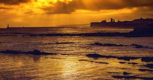 Free Silhouettes of Ruins on Sea Shore at Sunset Stock Photo