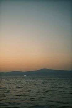 A peaceful sunset over the ocean with a distant ship on the horizon, offering solitude and calm.