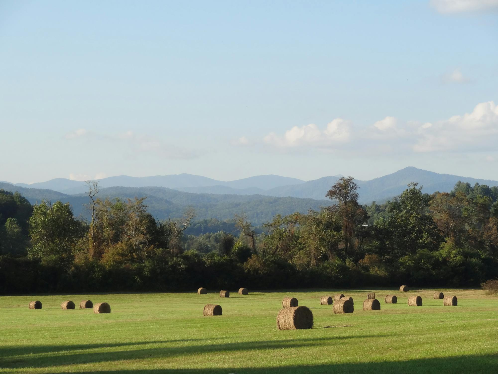 free photo of hay bales on field with blue ridge mountains in back